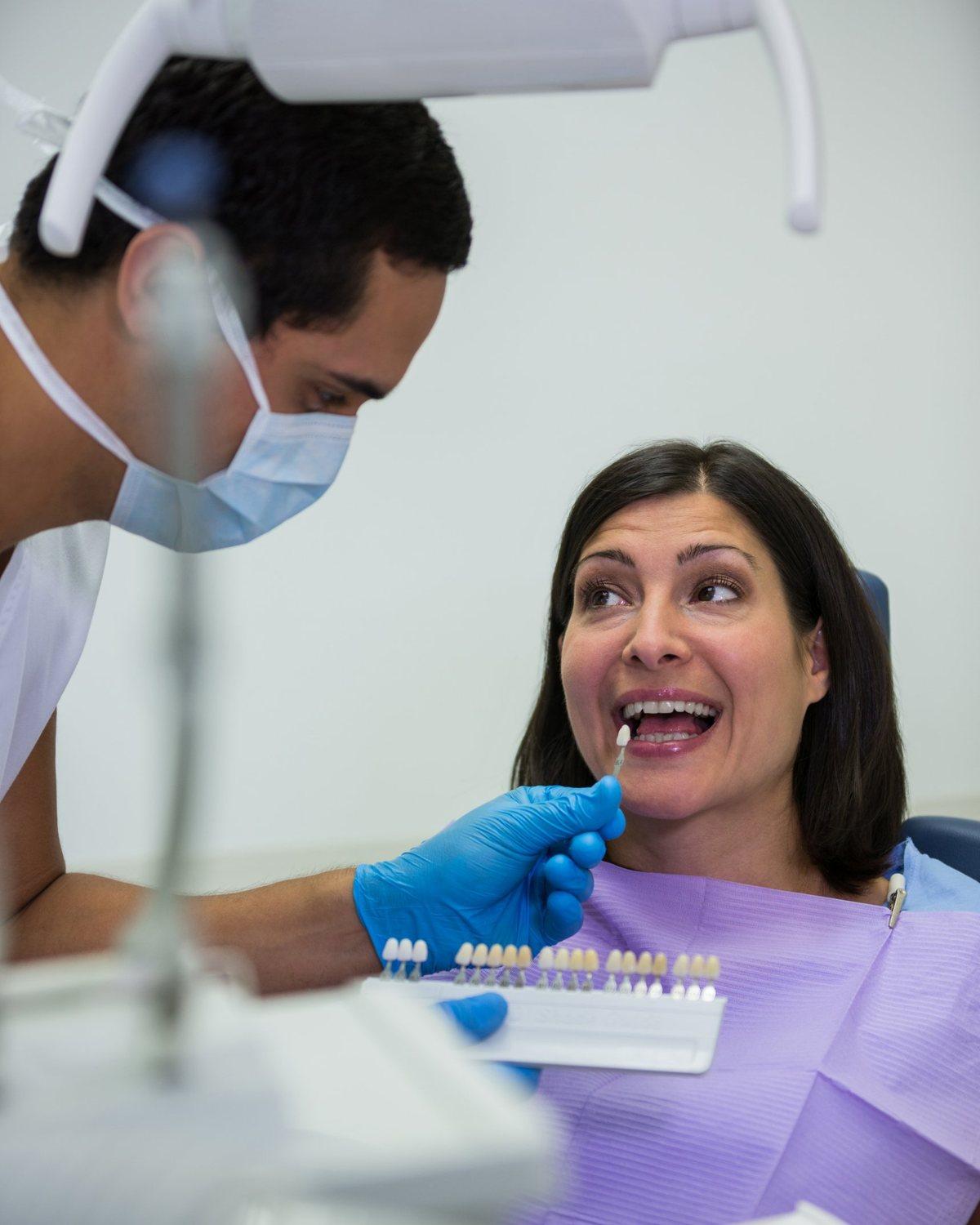 Dentista comparando el color de un diente con una guía de tonos